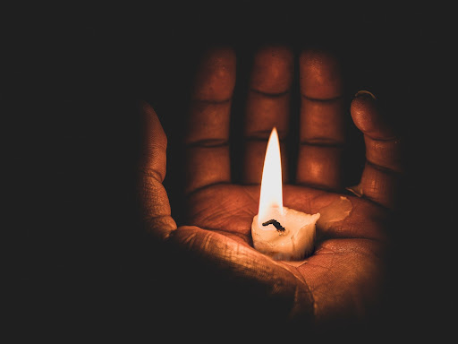 candle lit in the palm of a hand
