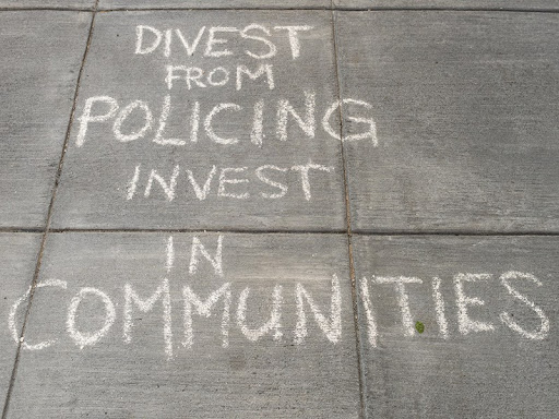 writing on sidewalk that says divest from policing invest in communities