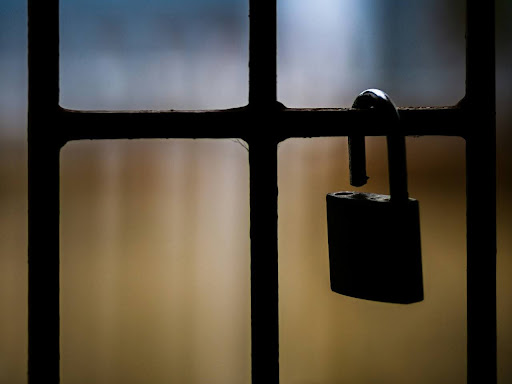 brass padlock on black metal fence 