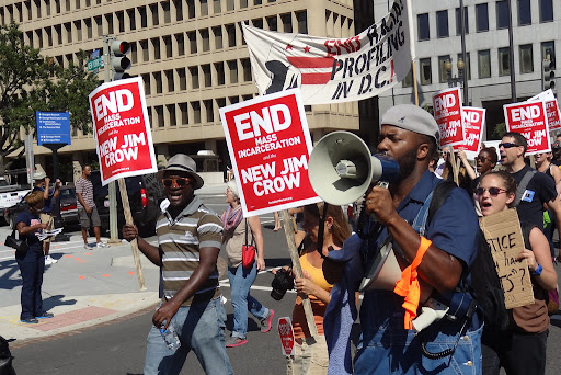 protestors holding signs that say end the new jim crow