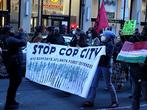 protestors holding banner that says stop cop city