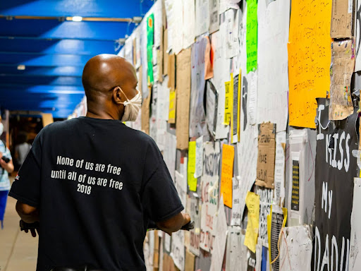 man in black crew neck t shirt standing beside yellow and white wall