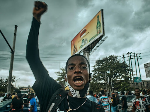 a man holding up a sign in front of a crowd with fist raised up