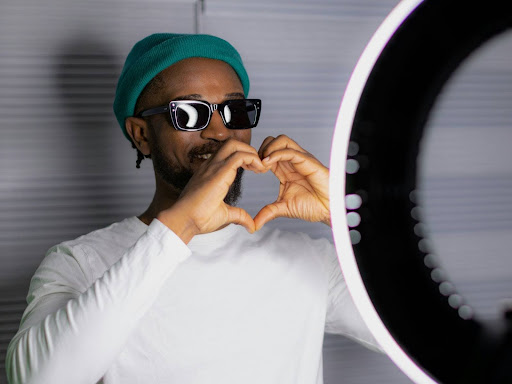 a man wearing sunglasses and a turban making a heart shape with his hands