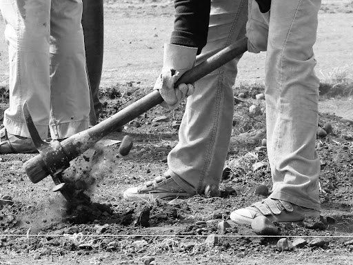 person with a pick axe digging a hole