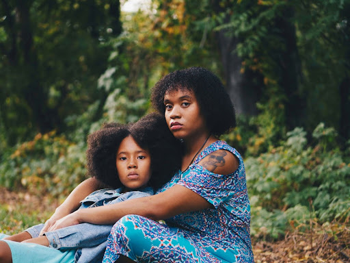 woman sitting in front of child sitting beside trees