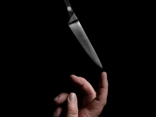 person balancing knife on the top of their finger