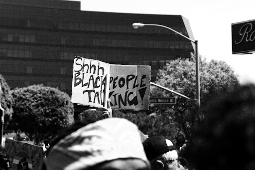 grayscale photo of man in white cap and black sunglasses holding sign