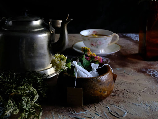 a table topped with a tea pot next to a vase filled with flowers