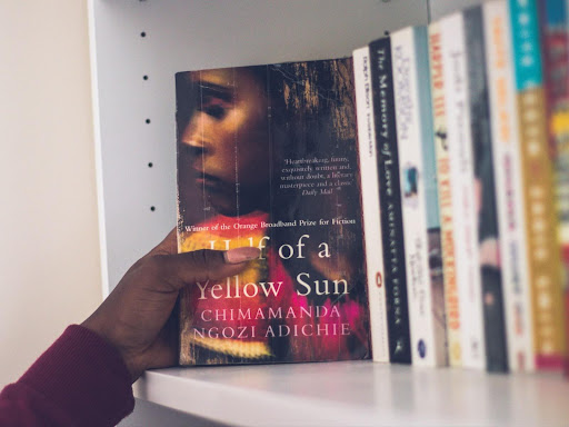 person pulling out a book from a bookshelf