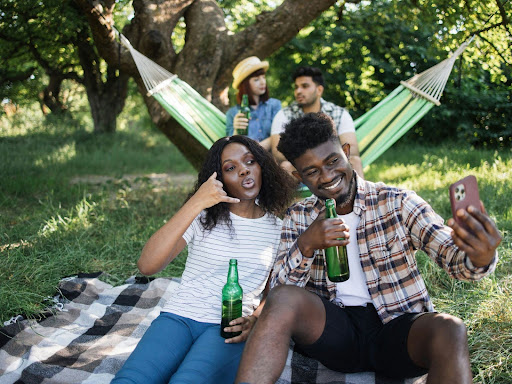 black man and woman relaxing at summer park taking a selfie
