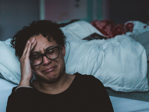 person sitting at the side of the bed with face crumpled up getting ready to cry