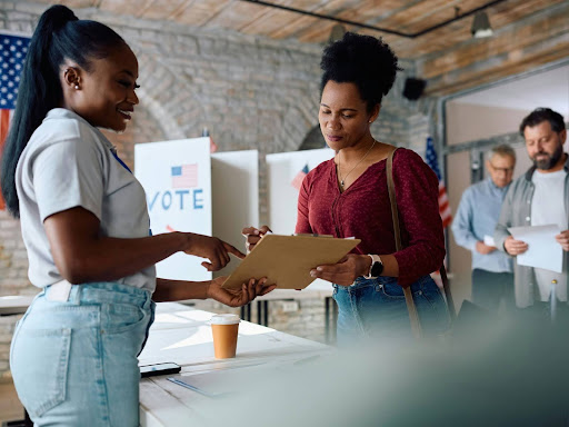 two black women showing each other what's on a ballot