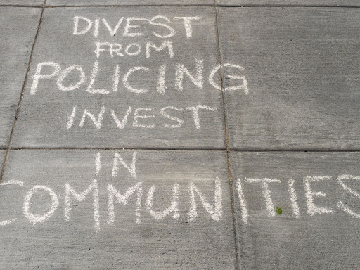 writing on sidewalk that says divest from policing invest in communities