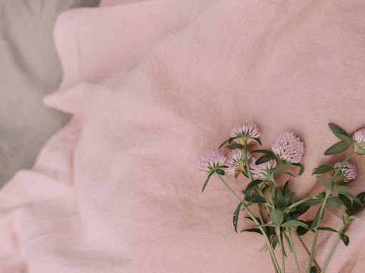 three flowers laying on a pink sheet