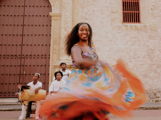 a woman in a colorful dress dancing in front of a group of people