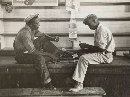 grayscale photo of two mean sitting on bench