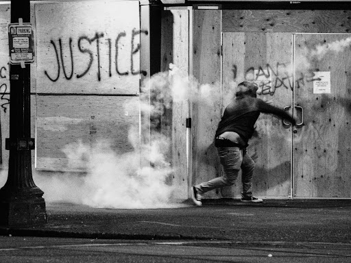 protestor in front of graffiti that says justice