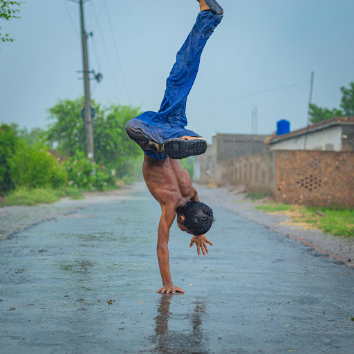 shirtless boy doing a handstand in the rain