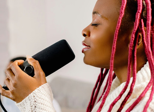 black woman with pink dreadlocks holding a microphone