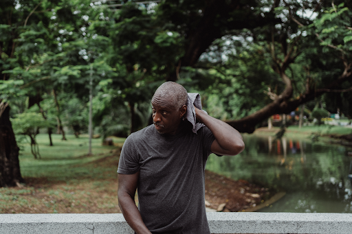 black man in gray crew neck t shirt wiping his sweat
