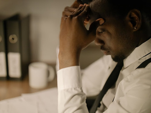 man in white long sleeves holding his head