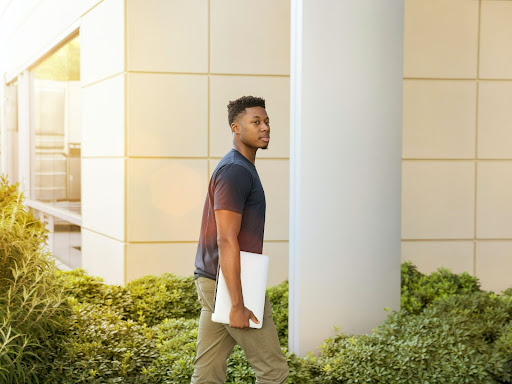 black man holding papers walking into a building