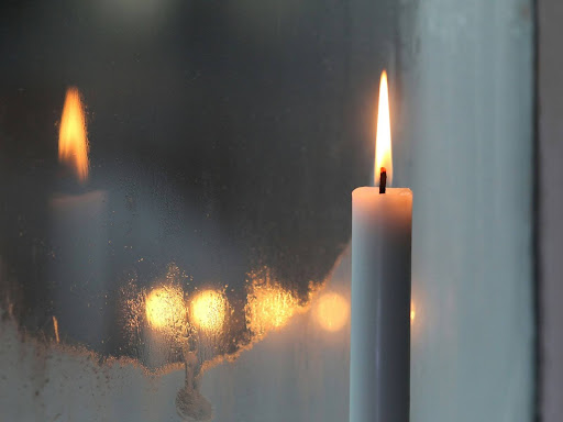 lit candle in front of a mirror