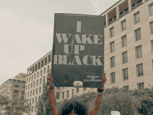 person holding sign that says i wake up black