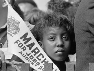 Young woman holds a "March For Jobs" banner