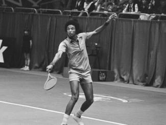 arthur ashe serving a tennis ball with a tennis racket