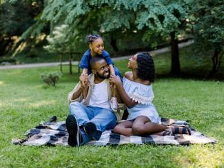 black family of three having picnic in park on summer day