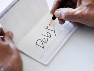 The word debt written in a checkbook