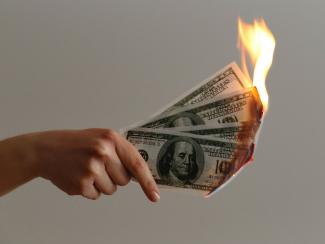 Hand holding burning money