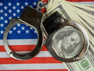 Money and handcuffs on American flag