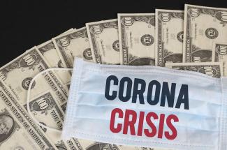 Surgical mask with words corona crisis on money pile
