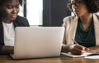 Two women behind laptop