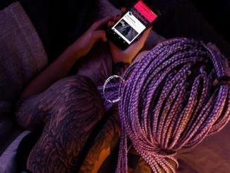 black woman with dreads looking at her phone