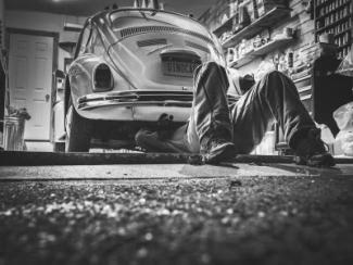 man under a car working on the car 
