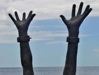 hands with shackles around the wrists reaching up