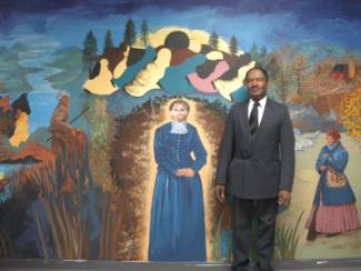 man standing next to a portait of harriet tubman 