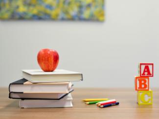 Books with an apple on top, pencils and A, B, C blocks on desk