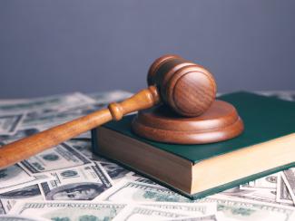 gavel on top of a book sitting on a pile of money 