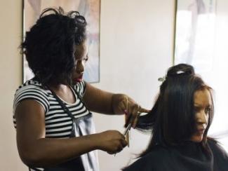 black woman hairdresser working on another black woman's hair 