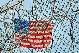 US Flag behind prison fence wire