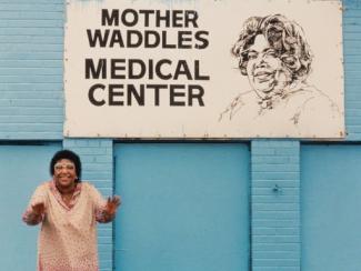 mother waddles standing in front a sign that reads mother waddles medical center 