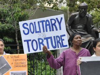 Woman holding "Solitary is Torture" sign