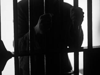 person grabbing jail cell bars