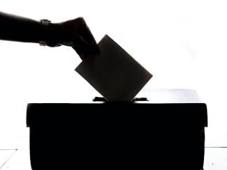 person putting a paper into a box with a slit 