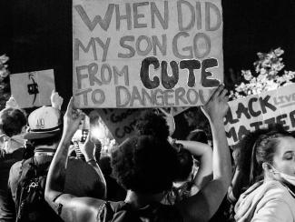 Demonstrators holding "When did my son go from cute to dangerous" sign